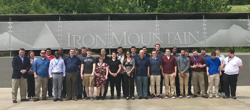Students and instructors standing in front of a wall that says "Iron Mountain"