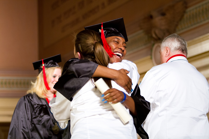 An image of a student smiling and hugging an instructor after receiving diploma