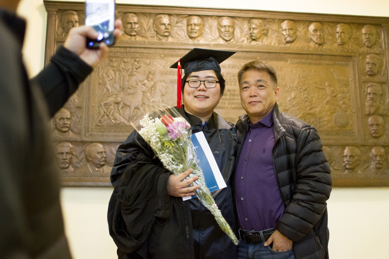 A student graduate and parent smiling for a picture at graduation