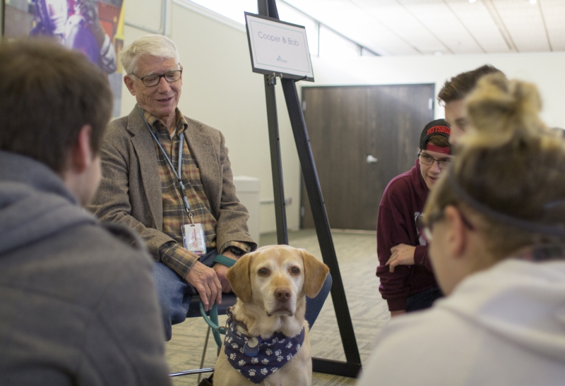 A man showing a therapy dog to students