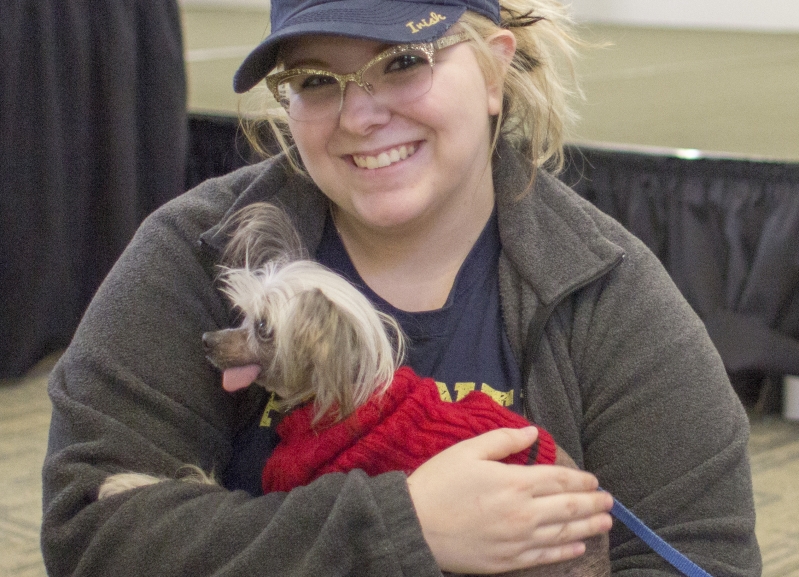 A woman smiling and holding a therapy dog
