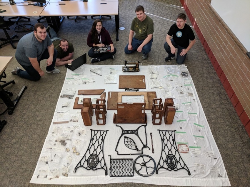 CAD students looking over parts of  a 1901 Singer sewing machine