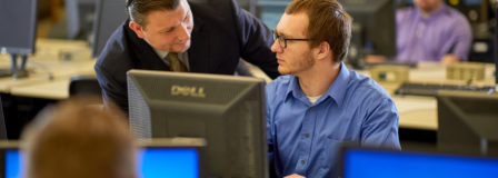 Two men talking at a computer