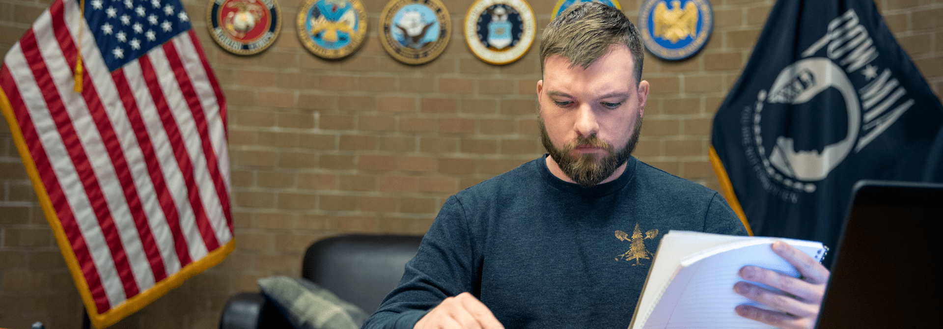 A military student sitting in the military lounge and doing schoolwork. 