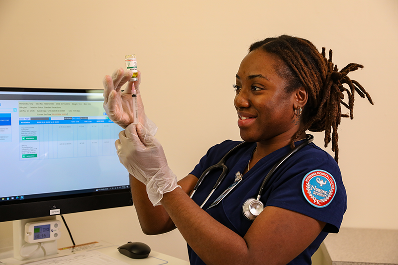 A photo of a nursing student practicing filling a syringe with medication.