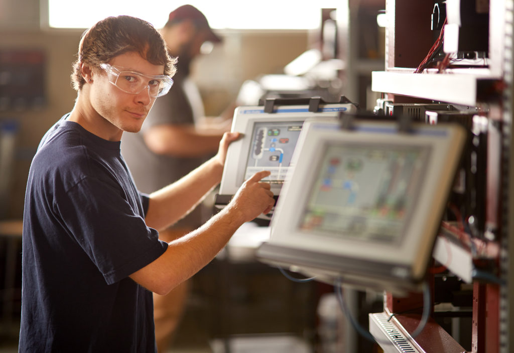 student working at the control panel of an industrial system
