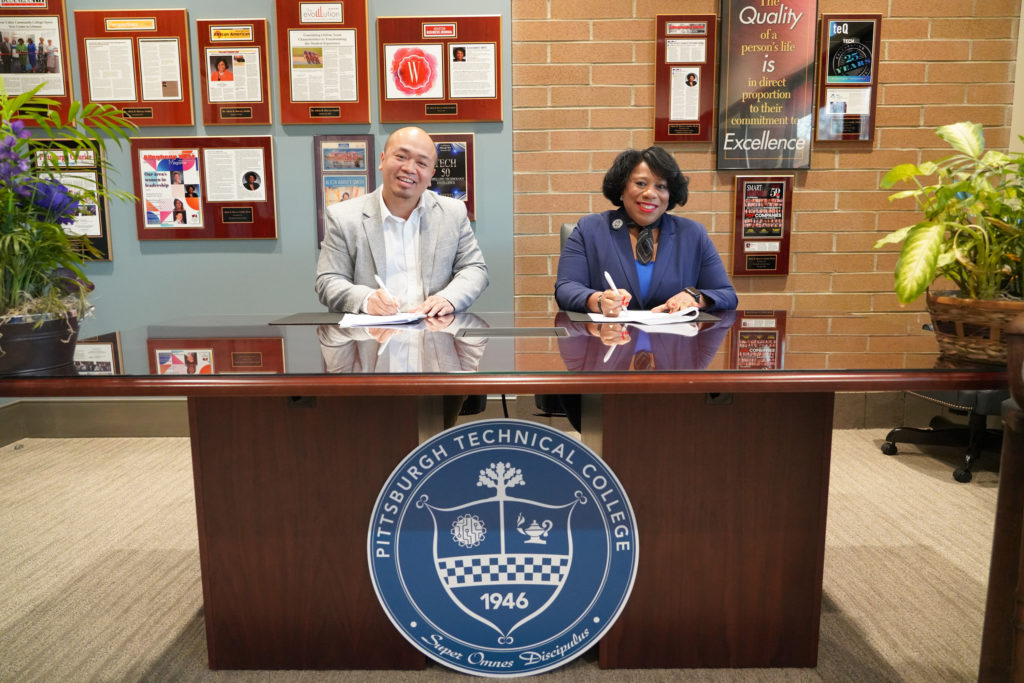 Dr. Alicia-Harvey Smith signing the Ceremonial Articulation Agreement with Vu Nguyen.
